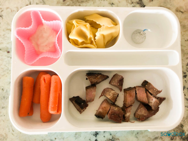 bento box with flank steak, carrots, ranch, tortellini, and Hershey kiss