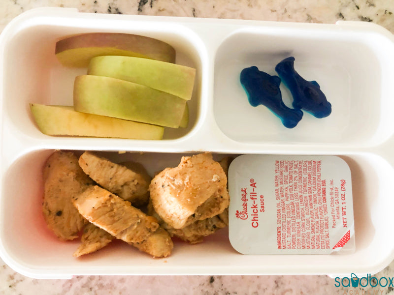 bento box with grilled chicken nuggets, chick-fil-a sauce, shark gummies, and apple slices