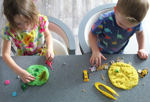 two kids playing with play dough and building their social skills